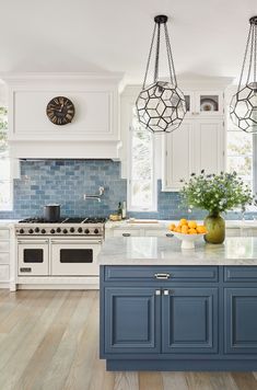 a kitchen with blue cabinets and an island in front of two clocks on the wall