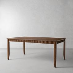 a wooden table sitting on top of a white floor next to a gray wall in an empty room