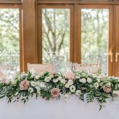 the table is set with flowers and candles for an elegant wedding reception in front of large windows