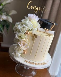 a graduation cake with white flowers and gold accents