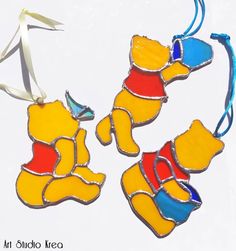 two winnie the pooh stained glass ornament hanging from a white ribbon on a white background