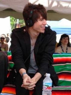 a man sitting on top of a bench next to a bottle of water and headphones