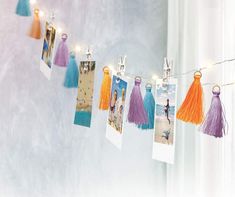 some pictures are hanging on a string with tassels and lights strung from them