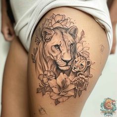 a woman's thigh with a lion and flower tattoo on her leg, which has the image of a baby in it