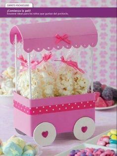 a pink wagon filled with popcorn and marshmallows on top of a table