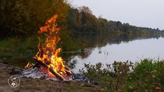 a campfire is lit on the shore of a lake