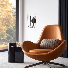 a brown chair sitting in front of a window next to a black table with a glass on it