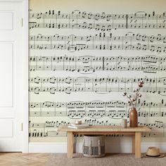 a wall with sheet music on it and a table in front of it, next to a door