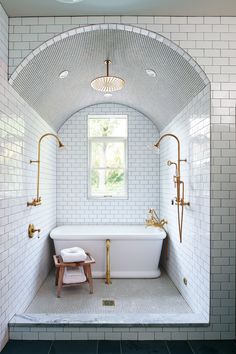 a bathroom with white tile and gold fixtures