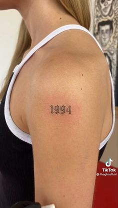 the back of a woman's shoulder with numbers tattooed on her left arm and chest