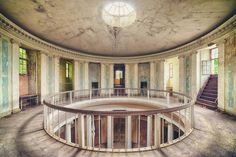 an empty circular room with stairs leading up to the second floor and windows on either side