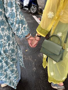 two people holding hands while walking down the street