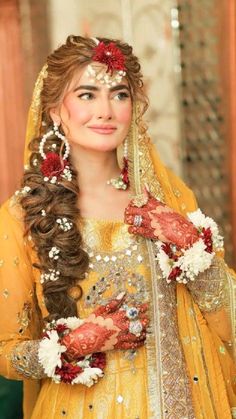 a woman wearing a yellow outfit with flowers in her hair and jewelry on her hands