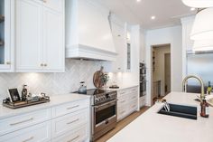 a kitchen with white cabinets and marble counter tops, along with an island in the middle