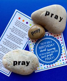 two rocks with words written on them sitting next to a prayer card and an open book