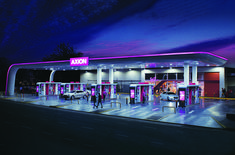 an empty gas station at night with people standing outside and cars parked in the lot