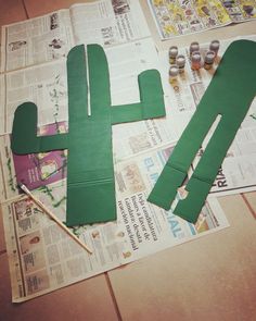 paper cut out to look like a cactus sitting on top of newspaper with paintbrushes next to it