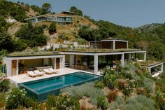 a house with a swimming pool in the middle of some trees and bushes on top of it