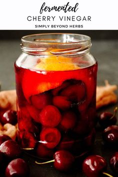 a jar filled with cherries sitting on top of a table