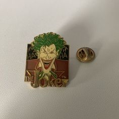 a joker pin sitting on top of a white table next to a pair of pins