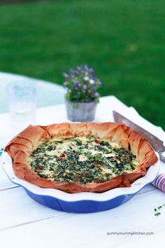 a quiche with spinach and cheese in a blue dish on a white table