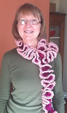 a woman wearing glasses and a pink crocheted scarf with purple flowers on it