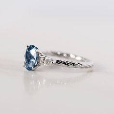 a close up view of a ring with a blue stone and diamond accents on it