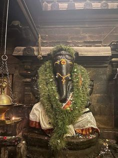 an elephant statue is adorned with greenery and bells