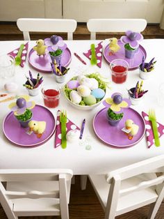 an easter table setting with purple plates and white chairs