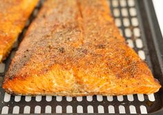 two cooked salmon fillets sitting on top of a black grill grate next to each other