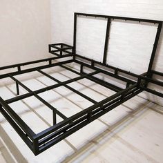 a metal bed frame sitting on top of a hard wood floor next to a white brick wall