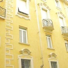 a yellow building with many windows and balconies on the front, and an iron balcony