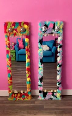 two brightly colored mirrors are in front of a pink wall and a blue couch is behind them