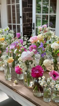 a table with many vases filled with flowers sitting on top of it's sides