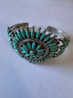 New without tags LOT : No JEWELRY TYPE : Bracelets TYPE : Bracelet BASE METAL : Sterling Silver STYLE : Cuff MAIN STONE : Turquoise Gorgeous Handmade Turquoise and Sterling Silver Cluster Cuff Bracelet. Beautiful craftsmanship! Cuff has an inside circumference of 6 inches with a 1 inch gap. Width is 2 1/4 inches. Stamped Sterling and Nizhoni. Such a pretty cuff. This listing is for 1 cuff only. Non native WILL VARY Thank you for looking at our items. Please contact us if you have any questions. 1/9/24 Unique Turquoise Bracelet Jewelry, Handmade Turquoise Bracelet Jewelry, Handmade Turquoise Bracelet, Turquoise Bangle Jewelry For Wedding, Traditional Turquoise Bracelets For Wedding, Turquoise Bangle Bracelets For Wedding, Traditional Round Turquoise Bracelet, Turquoise Bangle Bracelet For Weddings, Adjustable Turquoise Cuff Bracelet For Wedding