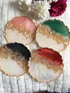 four different colored plates sitting on top of a white blanket next to flowers and peonies