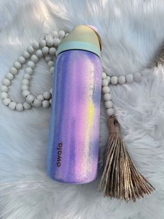 a purple and blue water bottle sitting on top of a white fur covered floor next to a tassel