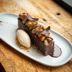 a piece of chocolate cake on a plate with ice cream and nuts in the middle