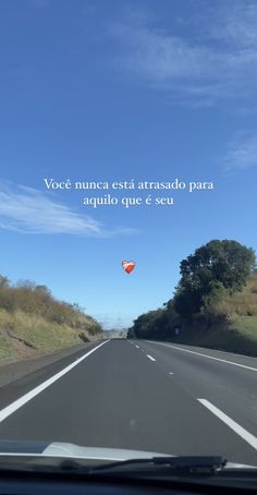 a view from the inside of a car driving down a road with a sky background