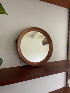 a round mirror sitting on top of a wooden shelf