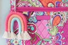 a colorful purse with a tassel hanging from it's front pocket and a pink handle