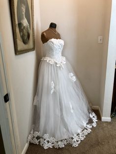 a dress is displayed on a mannequin next to a framed portrait in a room