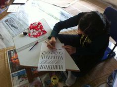 a person sitting at a table with some papers and pencils