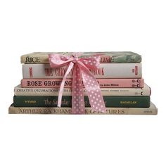 a stack of books with a pink bow on it's top and four other books in the background