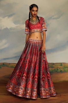 Red V-neck blouse with tribal print and threads, beads embroidery. Paired with coordinating lehenga and dupatta. - Aza Fashions Red V-neck Navratri Sets, Bohemian Embellished Choli With Traditional Drape, Red Choli With Motifs For Transitional Season, Red Bohemian Lehenga With Traditional Drape, Bohemian Red Lehenga With Traditional Drape, Bohemian Embellished Lehenga With Traditional Drape, Traditional Red V-neck Choli, Red Mirror Work Choli For Traditional Ceremonies, Red V-neck Choli For Navratri