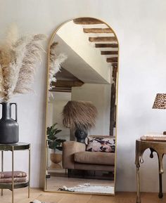 a mirror sitting on top of a wooden floor next to a table with a lamp