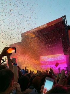 a large crowd at a concert with confetti in the air and people taking pictures