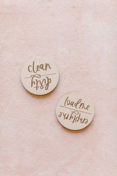 two wooden badges that say clean, happy and lead me on adventure are shown against a pink wall