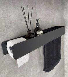 a black shelf with some bottles and candles on it next to a toilet paper roll