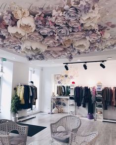 a clothing store with lots of clothes hanging from the ceiling and chairs in front of it